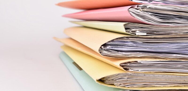 Close up of a stack of multi-coloured folders filled with files